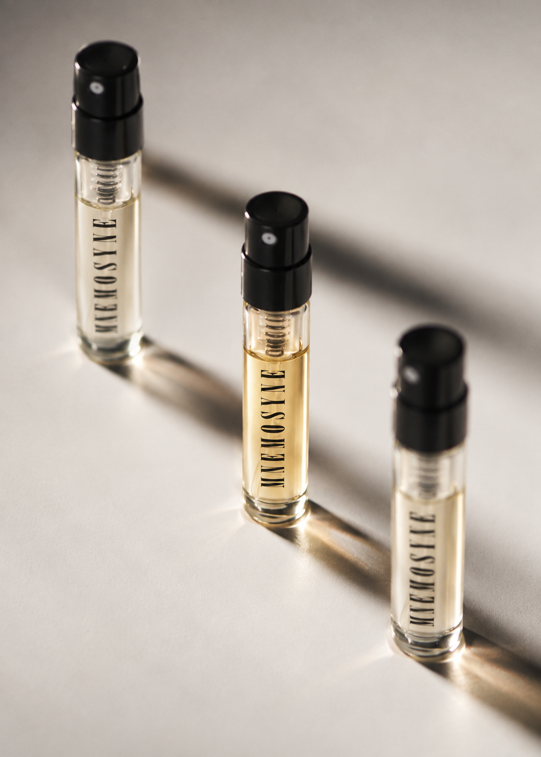 Three MNĒMOSYNE discovery set perfume sprays in directional light
